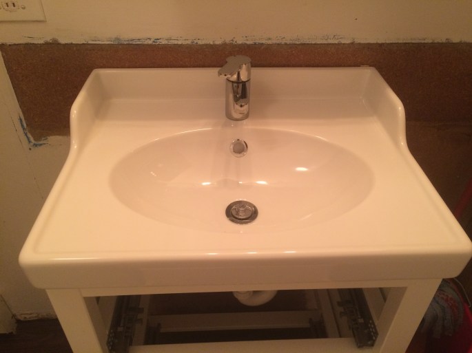 Handyman Rob Brown delivers handyman services for bathroom renovation in Vancouver, BC, Canada. He carefully installs faucets and sinks.